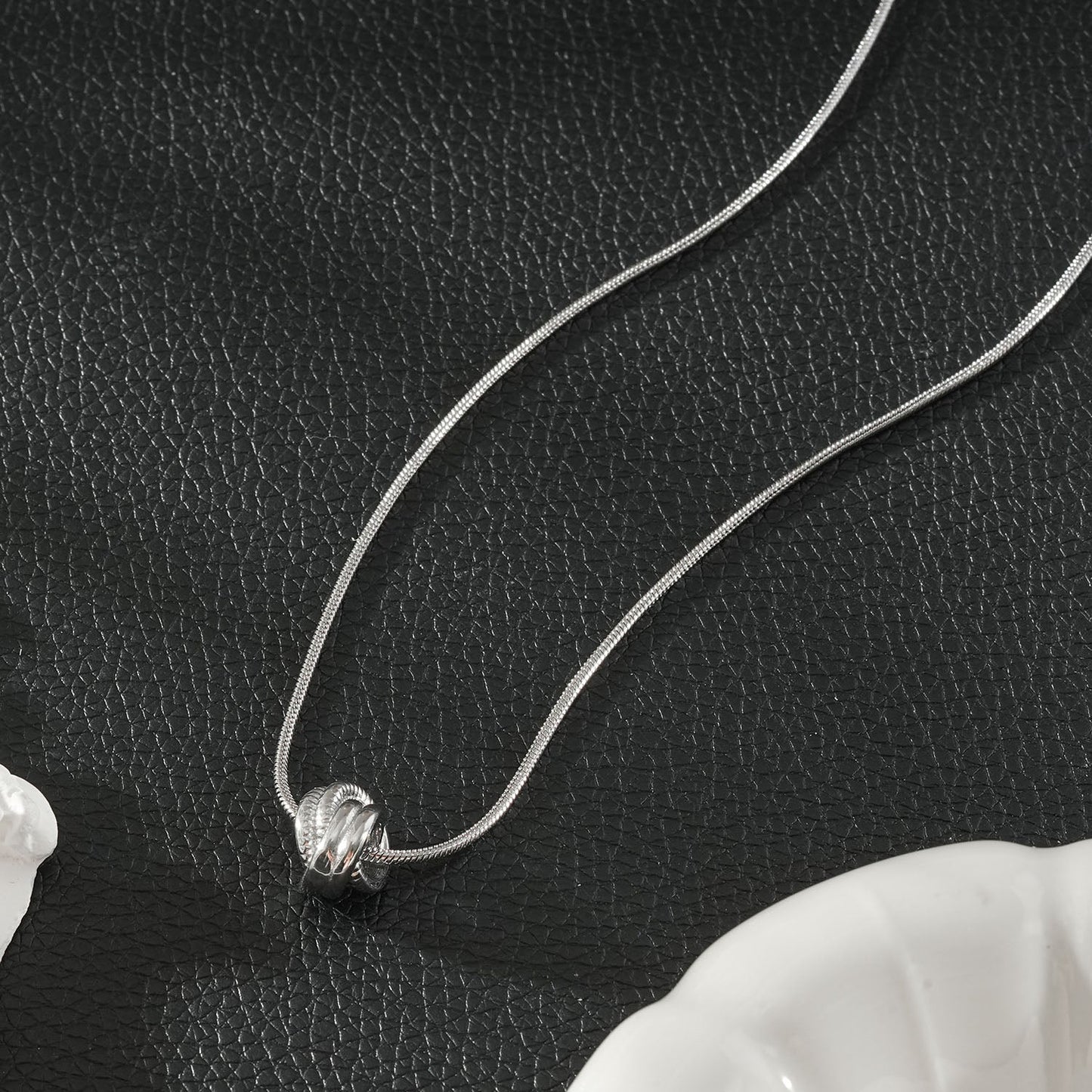 HACKNEY NINE Jewelry ALEKI Silver White Gold sculptural knot pendant necklace, showcasing intricate design on a sleek chain.