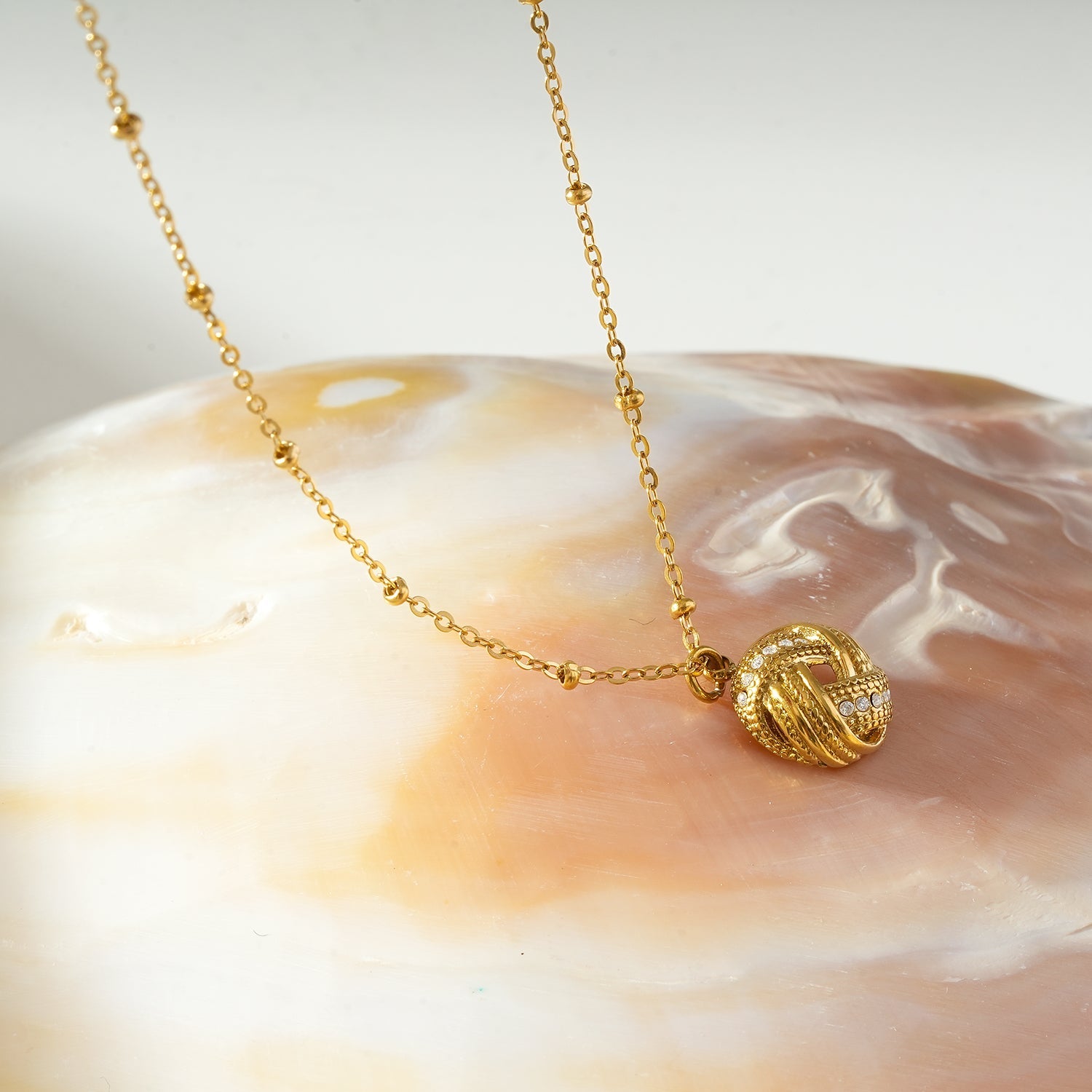 HACKNEY NINE Jewellery SALAMASINA Gold crystal interwoven knot pendant necklace with intricate design and sparkling gemstone accents.
